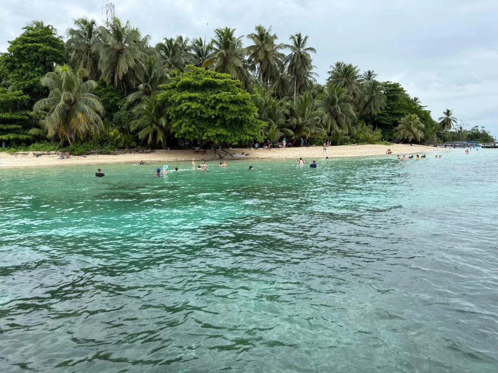 Grupo de visitantes relajándose frente al mar en la playa de Cayo Zapatilla